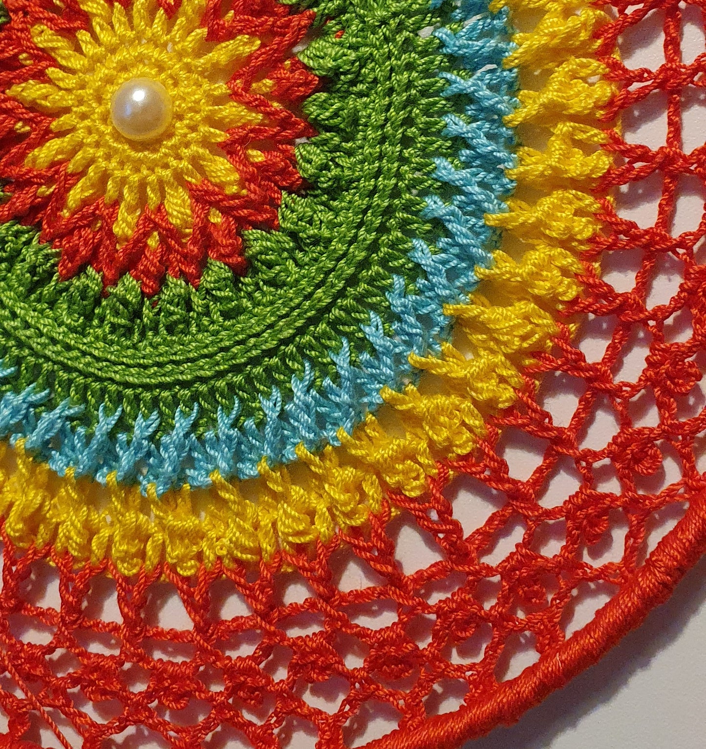 Colorful crocheted dream catcher with a pearl in the center
