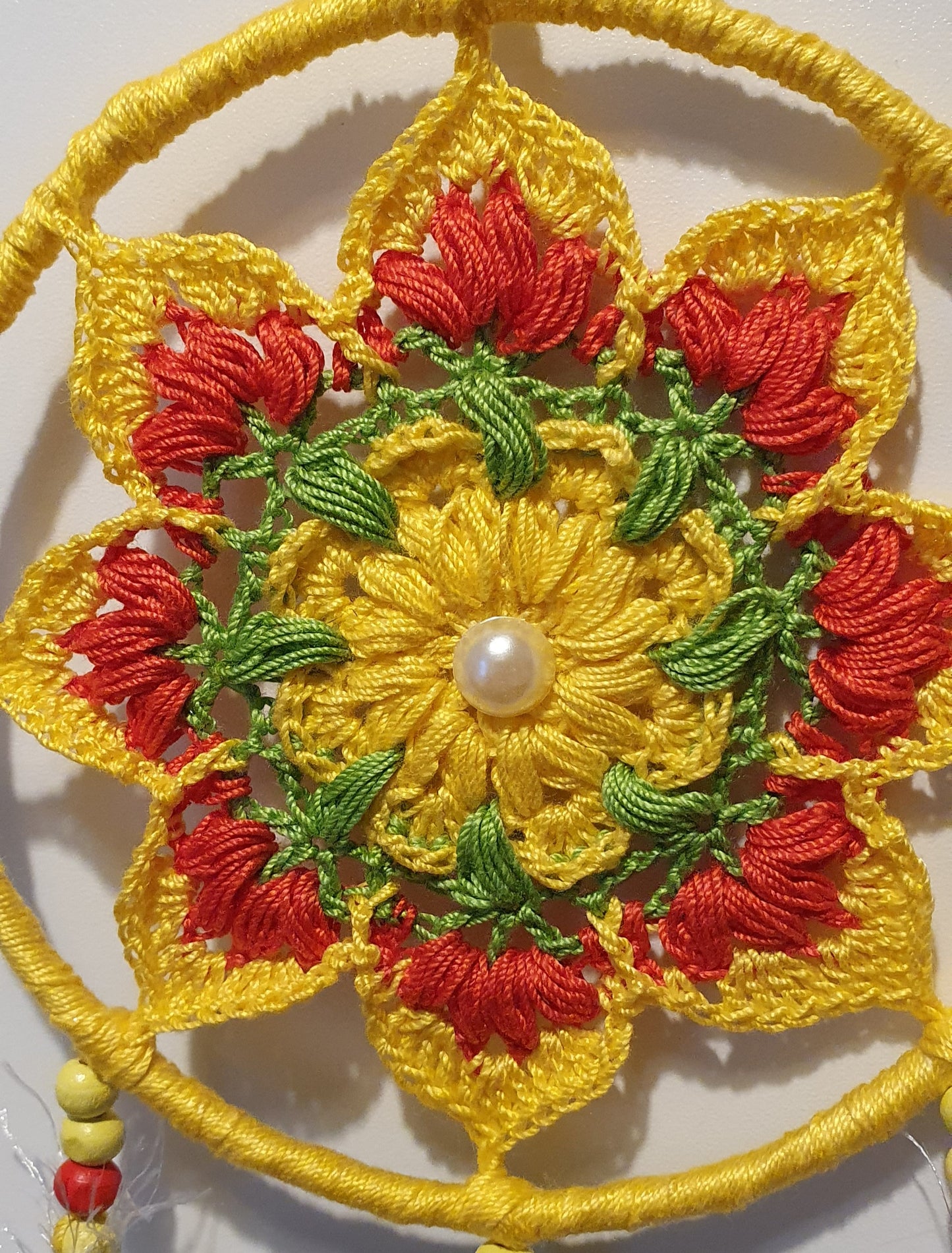 Crocheted yellow and red flower pattern with a pearl