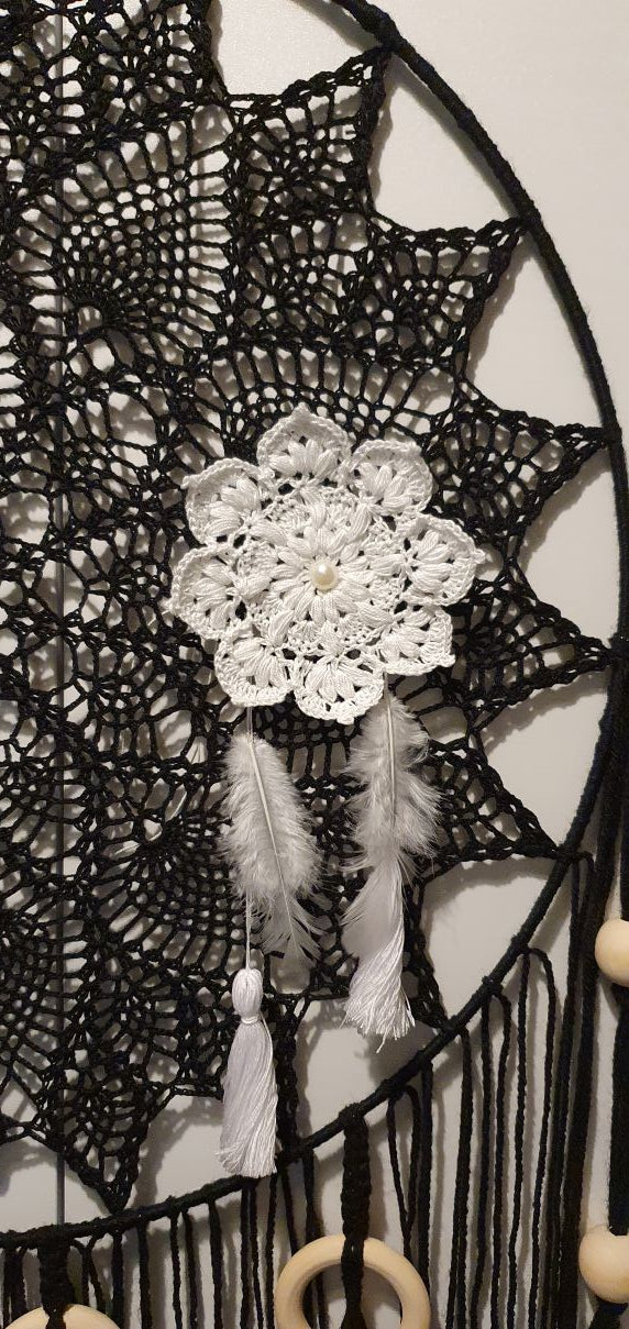 Decorative black lace fabric with a white floral brooch and feather