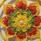 Crocheted yellow and red flower pattern with a pearl 