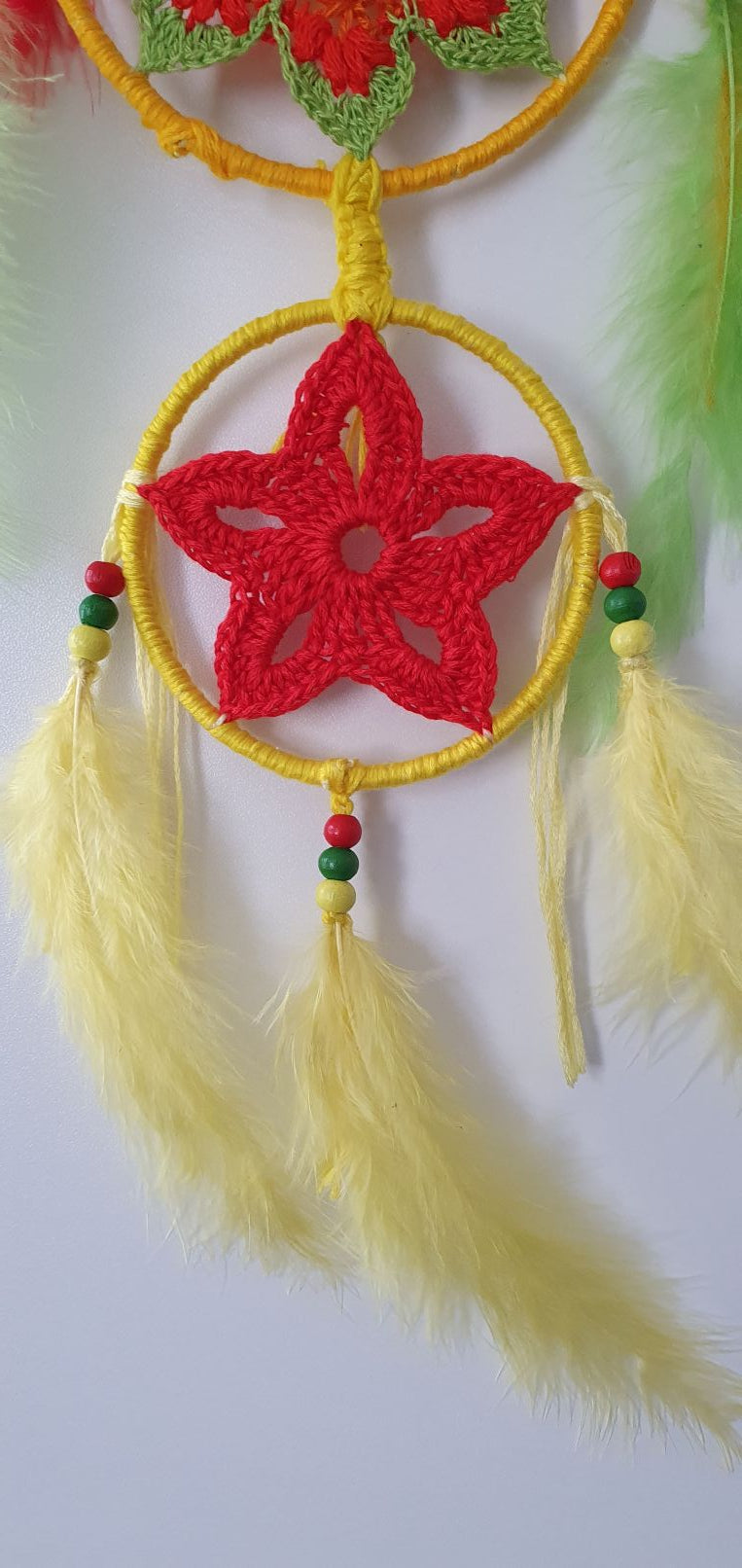 Decorative dreamcatcher with red center, yellow rim, and feathers 