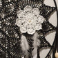 Decorative black lace fabric with a white floral brooch and feather