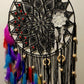 Black lace dreamcatcher with colorful feathers and beads on a white wall