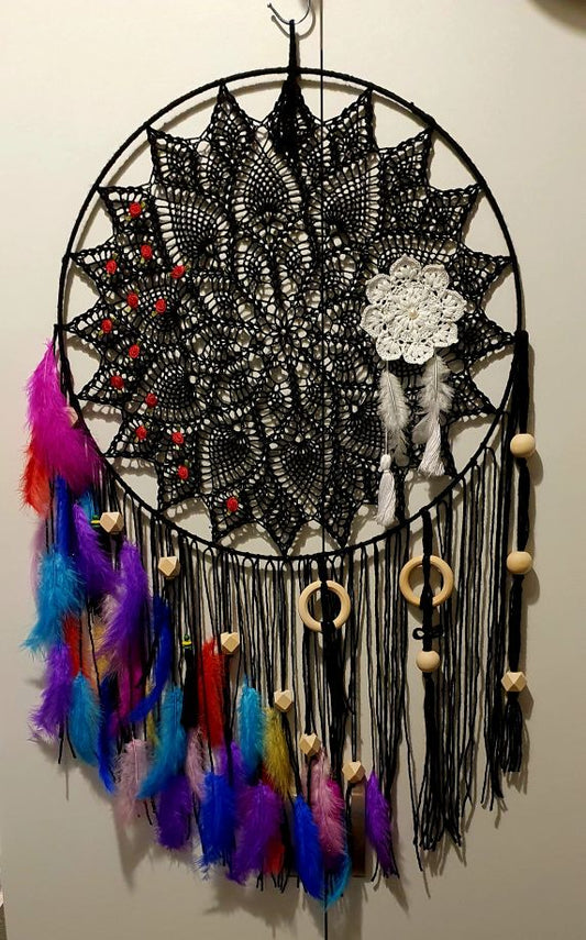 Black lace dreamcatcher with colorful feathers and beads on a white wall